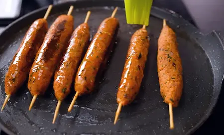 shaping soyabean seekh onto skewers and cooking them in a pan