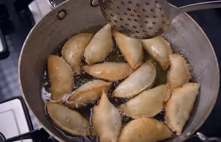 Frying Holi Special Matar Gujiya in hot oil until golden brown