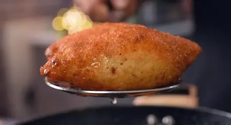 Deep frying Dahi Ke Sholey recipe rolls until crispy and golden brown