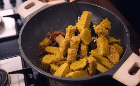 Step 7: Tossing Dudhi Muthiya pieces in tadka until golden and crispy
