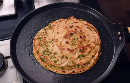 Step 9: Cooking Mirch Laccha Paratha on a hot tawa with oil until golden and crispy