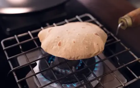 Step 2: Rolling and cooking phulka on tawa to serve with Bhujia Shing Ki Sabzi