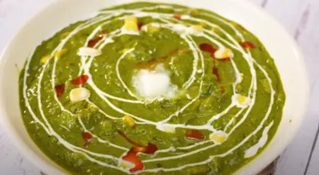 Finished Palak Corn Ki Sabji garnished with white butter and fresh cream, ready to serve.