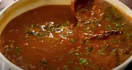 Pouring reserved stock and adding tomatoes and spices into the Ulavacharu. and garnishing