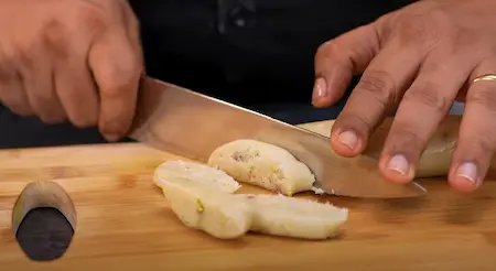 Cylindrical dough portions being cut into slanted pieces for the shakarpara preparation.