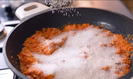 Sugar being mixed into Gajar Halwa for sweetness