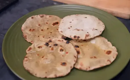 Bajra Rotla being rolled and cooked on a tawa until golden brown