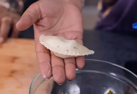 Rolling and shaping the gujiyas with stuffing in the center