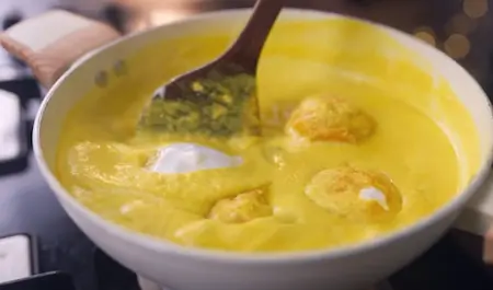 Step 4: Adding whisked curd to Mango Curry on low flame to prevent splitting