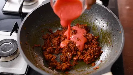 Tomato puree being added to the masala base for the Soya Dum Aloo curry.