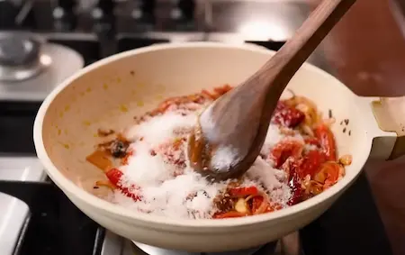 Incorporating desiccated coconut into the onion-tomato mixture for Peanuts Ki Sabji.