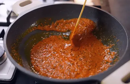 Cooking coconut paste with spices for Malai Pyaaz ki Sabzi