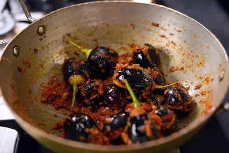 Adding stuffed brinjals to the gravy and simmering