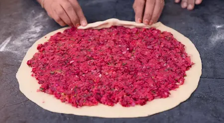 Spreading stuffing on dough for Pinwheel Aloo Paratha