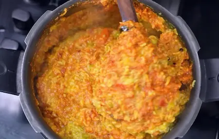 Vaghareli Khichdi cooking in a pot with spices and vegetables