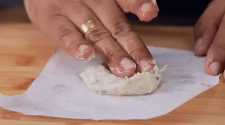 Shaping urad dal batter on banana leaf and sliding into oil for Udid Daliche Vade recipe