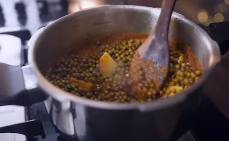 Step 3: Adding diced potatoes and soaked kala vatana to the masala in pressure cooker for Kala Vatana Usal