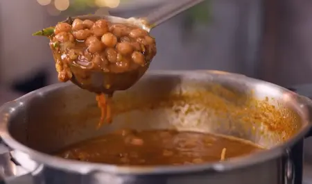 Step 4: Pouring ghee tadka with ginger and green chilli juliennes over Peepé Wale Chole Kulche