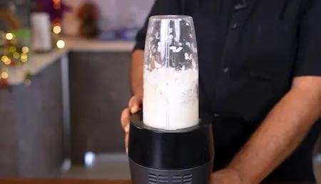 Blending poha, suji, and curd for a smooth batter consistency.