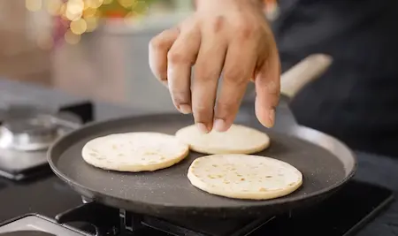 Pre-cooking mini pizza bases on a tawa until golden.