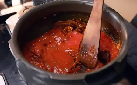 Adding tomato puree to the masala