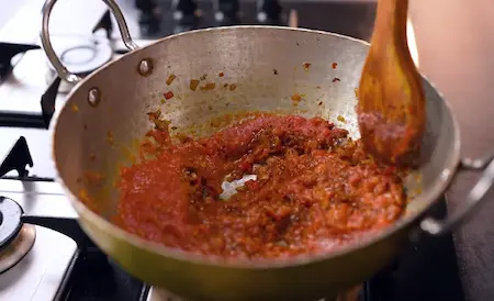 Cooking the gravy for Kathiyawadi Baingan with onions and tomatoes