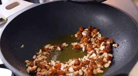 Golden nuts being sautéed with mashed carrots for Gajar Halwa