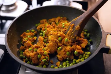 Cooking and mixing bread samosa stuffing with potatoes and peas