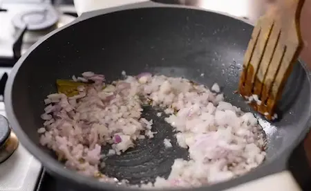 Sliced onions frying in oil until golden brown for making a paste.