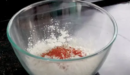 A bowl of seasoned flour mixture prepared for coating Chicken Popcorn.