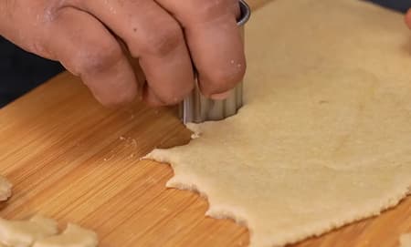 Cutting dough into small crescent shapes for frying.