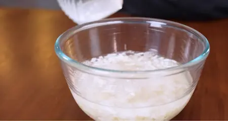 Rinsing and straining poha for no bread sandwich recipe.