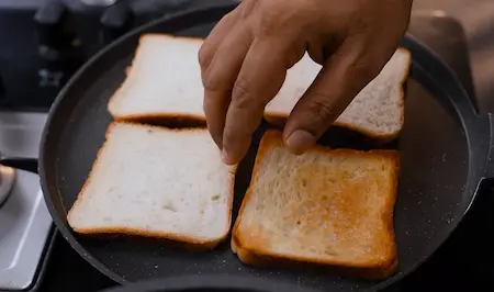 Golden toasted bread on a pan, ready to be cut into squares.