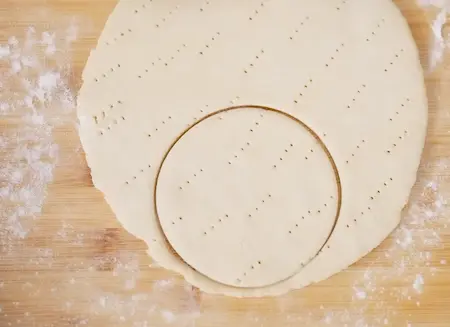 Rolling and cutting out mini rounds from pizza dough.