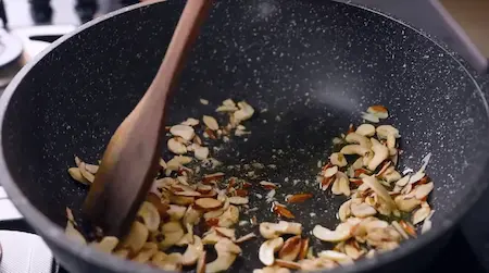 Roasting dry fruits like cashews, almonds, pistachios, and raisins in ghee for Pinni Laddu