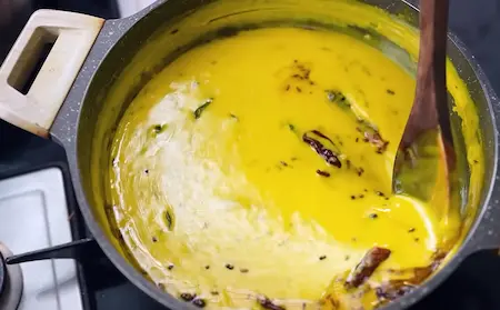 Preparing Kathiyawadi Kadhi with mixed spices in a pan