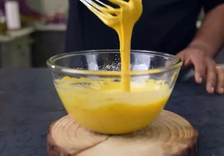 Mixing besan batter with ajwain and turmeric for Dabeli Pakoda Sandwich