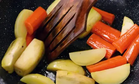 Step 3: Sautéing potatoes, raw banana and carrots in mustard oil for Niramish Jhol