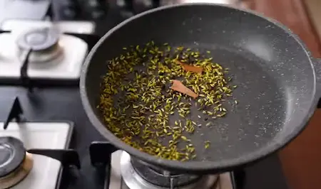 Roasting whole spices like cinnamon, cloves, and cardamom in a dry pan.