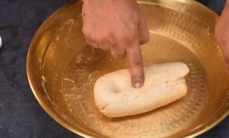 Mixing wheat flour and suji with oil for a crumbly dough texture.