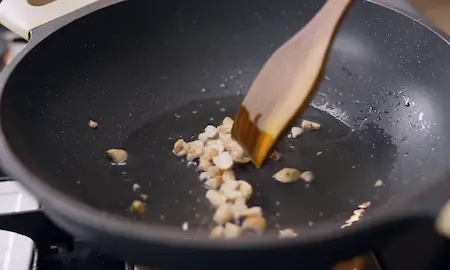 Cashew nuts frying in a pan until golden brown