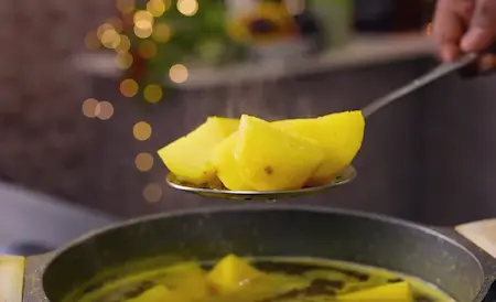 Potatoes boiling in a pot with water, salt, and turmeric