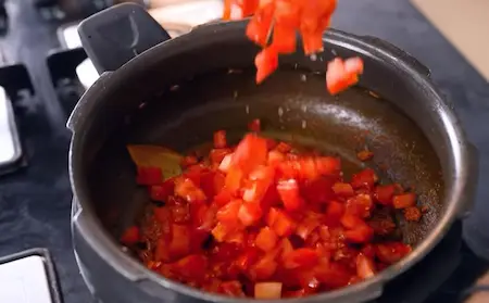 Adding tomatoes and herbs to the dish