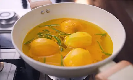Step 1: Boiling whole peeled mangoes with green chillies, curry leaves and turmeric for Mango Curry