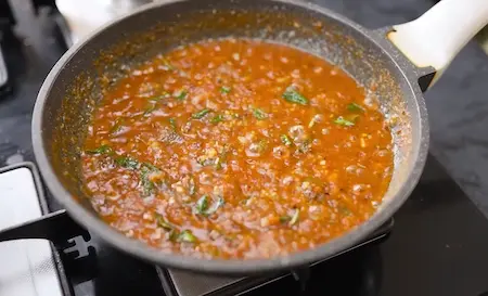 Cooking onion, garlic, and spices for pizza sauce on medium heat.