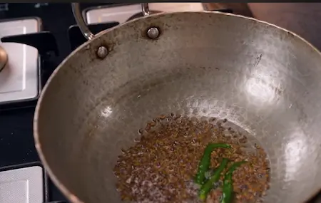 Tempering jeera, green chilies, and hing for Aloo Chana Sabzi