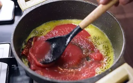 Cooking ginger green chilli paste and tomato puree for dum aloo masala