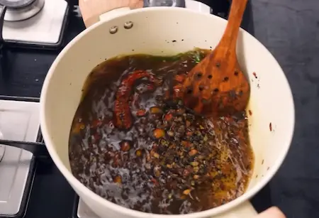 Cooking Bhatt ki Batauani with spices